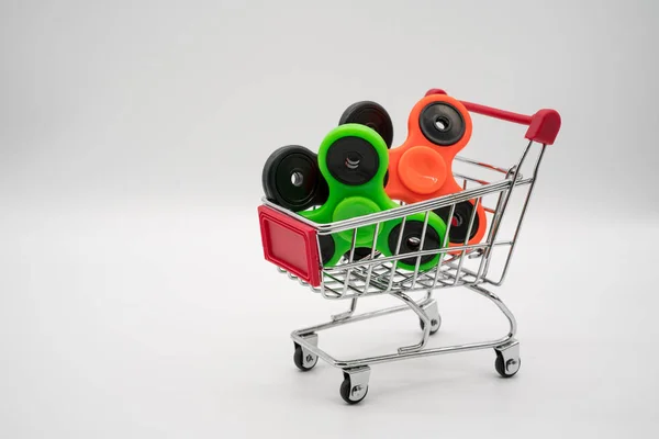 Carrinho de compras com spinners coloridos — Fotografia de Stock