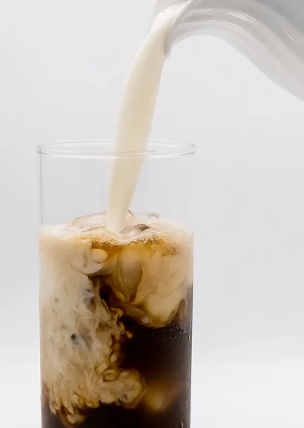 Milch in ein Glas Kaffee gießen — Stockfoto