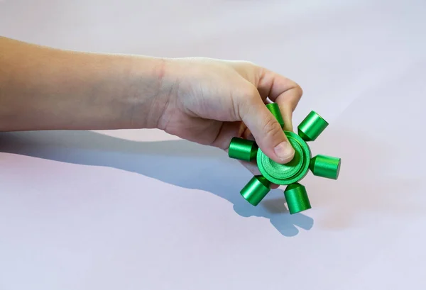 Mano del capretto che tiene lo spinner verde del fidget — Foto Stock