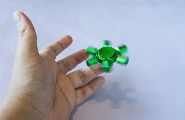 Mano de asiático hombre spins verde fidget spinner — Foto de Stock