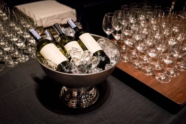 Sparkling wine bottles in ice bucket on wooden table — Stock Photo, Image