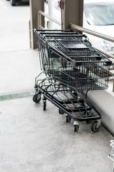 Row of black shopping cart with black handle lined up on cement — Stock Photo, Image