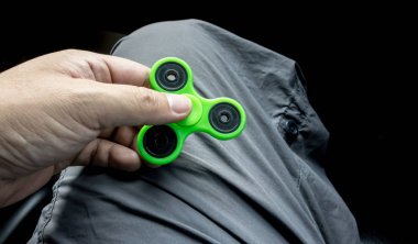 Plastik yeşil tri topluca spinner tutan el
