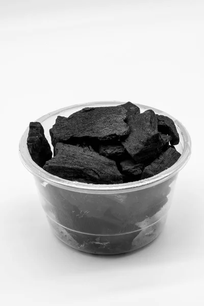 Натуральный древесный уголь в пластиковой чашке изолированы на белом — стоковое фото