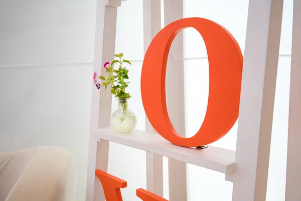 Πορτοκαλί αλφάβητο στο ράφι λευκό με λουλούδι — Φωτογραφία Αρχείου