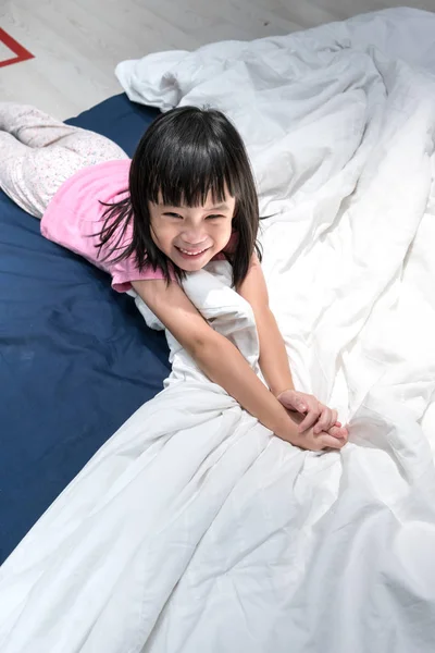 Anak asia yang bahagia baru saja bangun di tempat tidurnya — Stok Foto