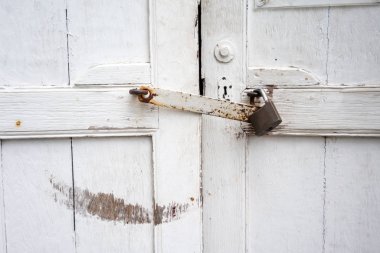 Beyaz boyalı ve paslı lat ile kilitli antika kapalı kapı
