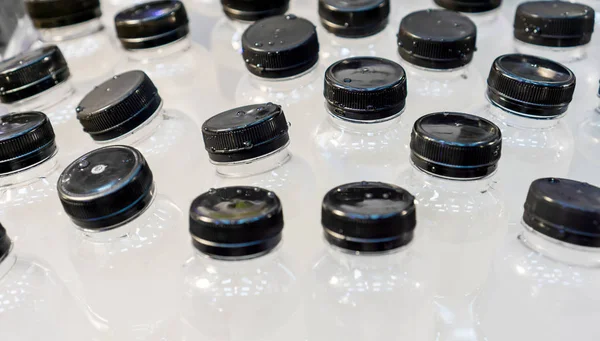 Cold water bottles with black caps in ice box. — Stock Photo, Image