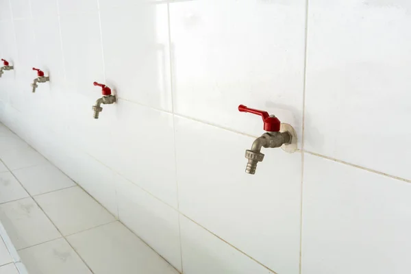 Rij van rode water kranen tegen de witte muur — Stockfoto