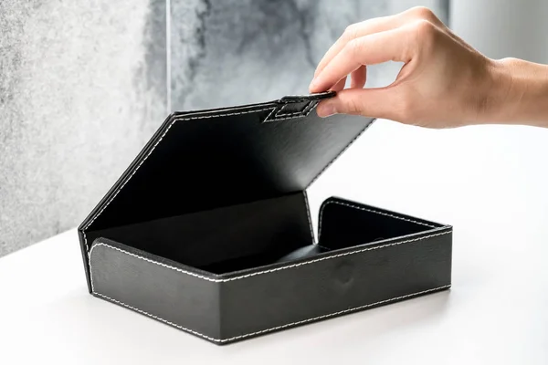 Señora mano derecha apertura caja de cuero negro en escritorio blanco — Foto de Stock