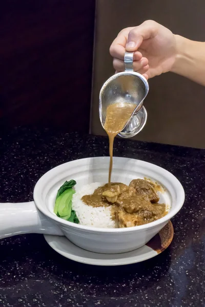 Mão derramando molho de carne cozida molho de carne em arroz com carne assada — Fotografia de Stock