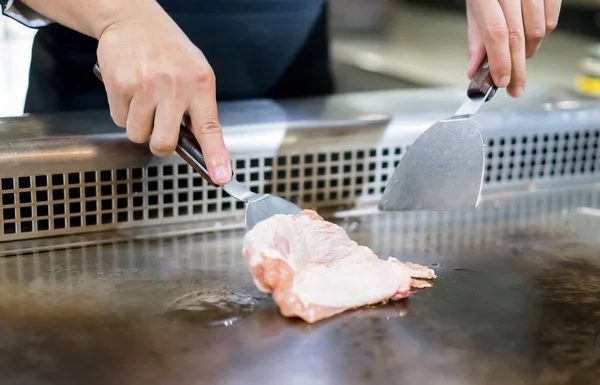 Mão do Chef cozinhar bife de frango na panela quente na frente do costume — Fotografia de Stock