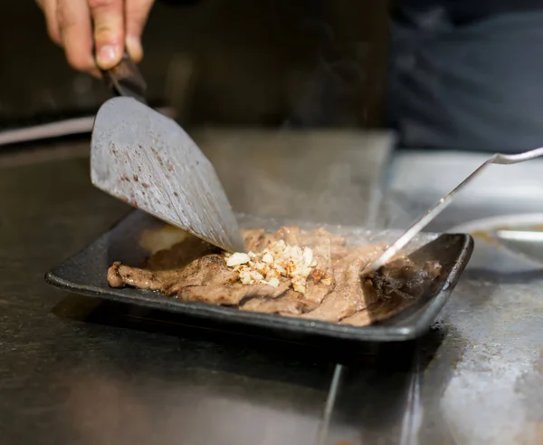 Mão do Chef cozinhar bife na panela quente na frente dos clientes — Fotografia de Stock