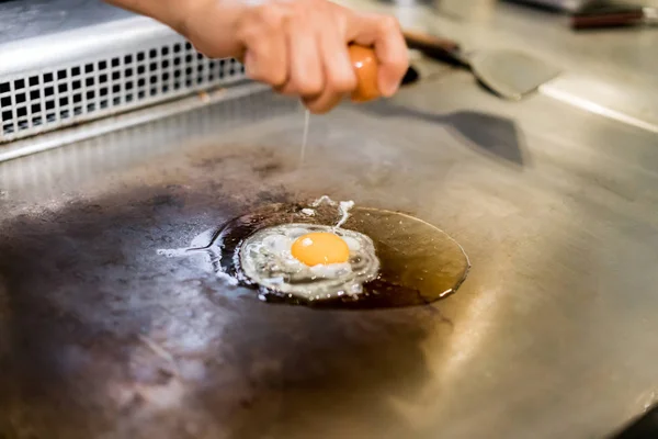 Mão do Chef cozinhando ovo na panela quente na frente dos clientes . — Fotografia de Stock
