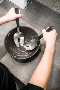 Üzerinde siyah porselen yemek kaşık ve çatal tutan eller kadın 