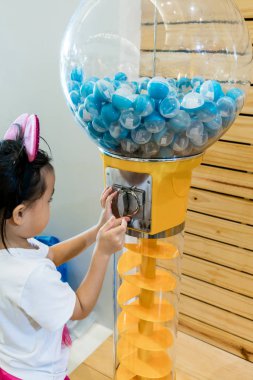 Asyalı kız şanslı oynarken top vending machine çizmek.