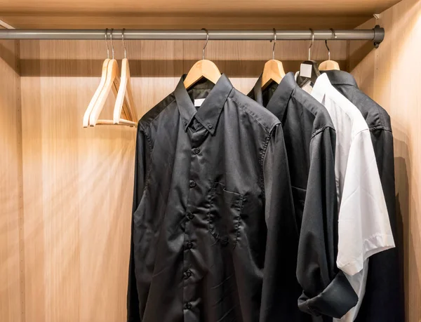 Camisas básicas pretas penduradas no armário . — Fotografia de Stock