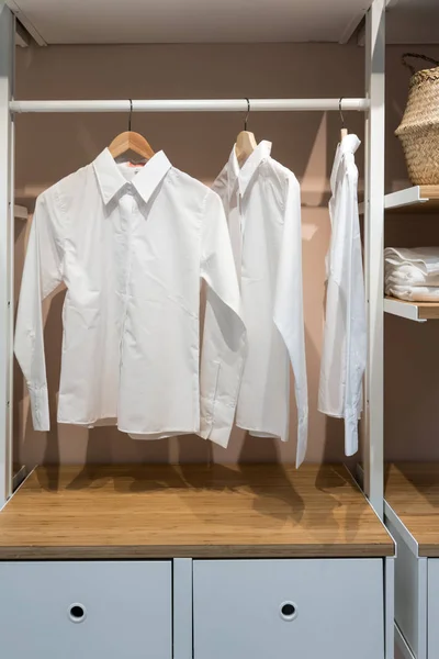 Camisas básicas brancas penduradas no armário com gaveta — Fotografia de Stock