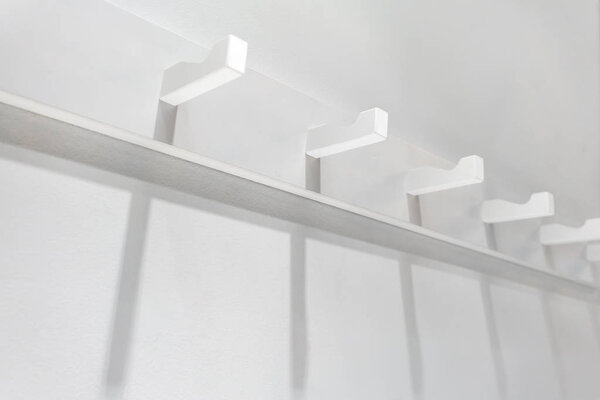 White wooden wall hanger mounted against white wall.