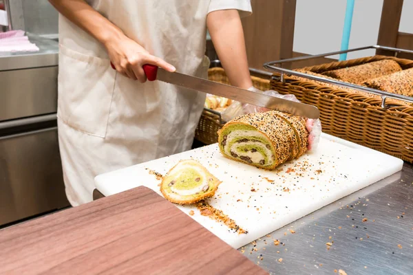 Mão do chef cortando pão de chá verde na placa branca . — Fotografia de Stock