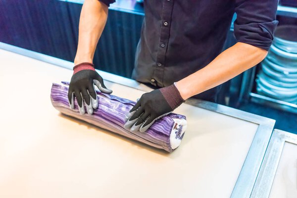 Hands of chefs rolling and mixing small colorful sugar rolls int