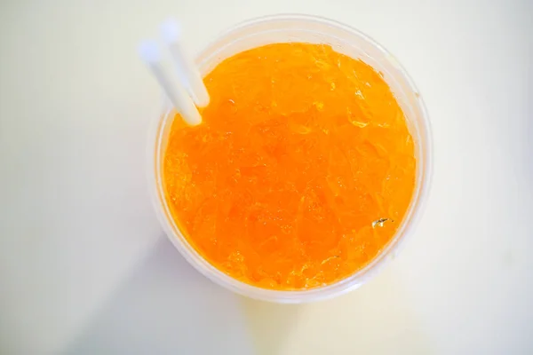 Golpe afrutado naranja con hielo triturado en taza de plástico con doble —  Fotos de Stock