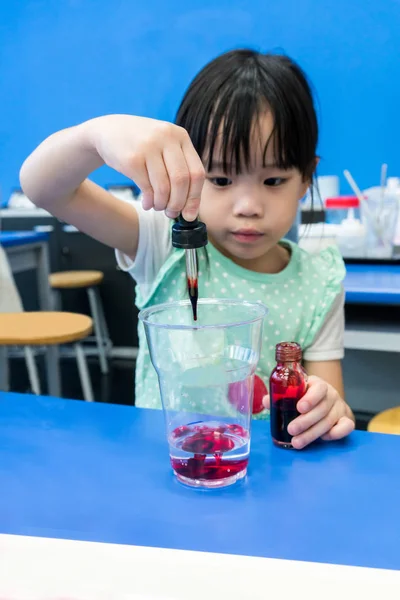 Детский сад девушка с помощью капли, чтобы добавить красный цвет в чашку на B — стоковое фото