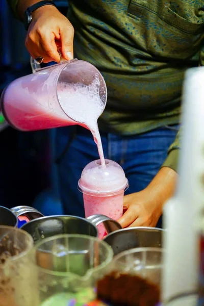 Professional hand pouring pink sweetened milk with shaken milk f — Stock Photo, Image