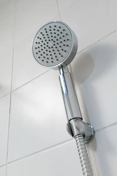 Silver circle shower head hanging against white ceramic tile wal — Stockfoto