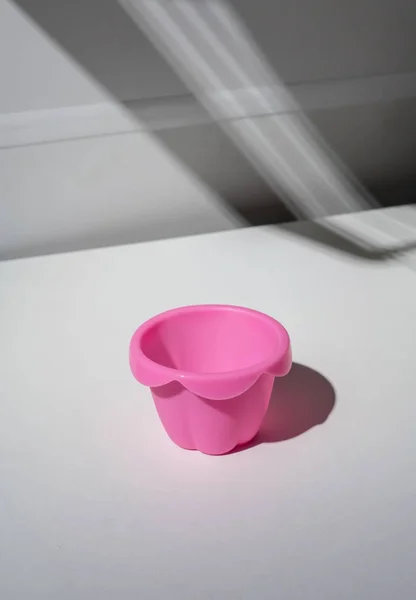 Vuoto tazza di silicone rosa e l'ombra gettata isolato su ta bianco — Foto Stock
