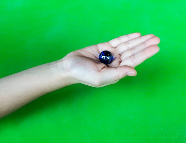 Mano de niño sosteniendo mármol de cristal azul con un reflejo — Foto de Stock