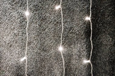 Koyu gri kumaş doku karşı asılı yıldızlı aydınlatma zinciri.