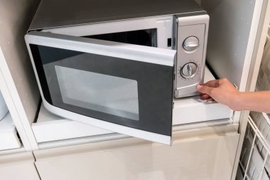 Mikrodalga kapıyı açmak için düğmeye basarak kadının elleri