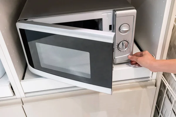 Woman's Hands pressing button to open microwave door — Stock Photo, Image