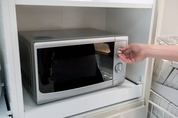Manos de mujer ajustando el botón de calor en el microondas — Foto de Stock