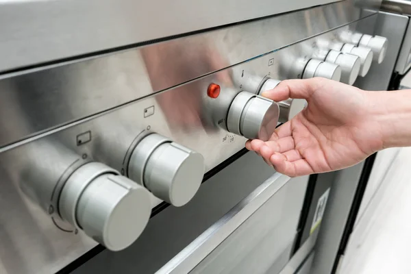 Manos de mujer ajustando el botón de calor en la máquina del horno — Foto de Stock