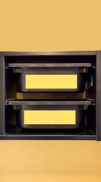 Black plastic storage bin with yellow label for room organizer