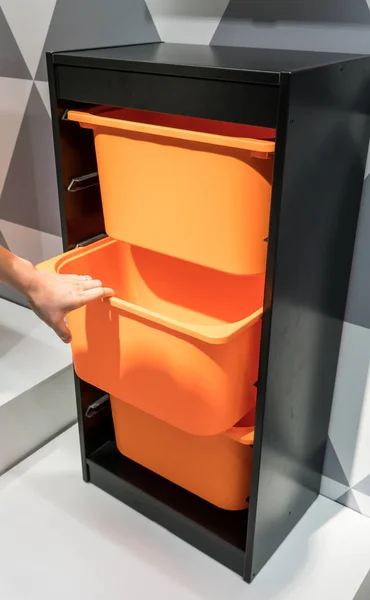 Жінка рука тримає апельсиновий пластиковий ящик для зберігання в чорній кабіні — стокове фото