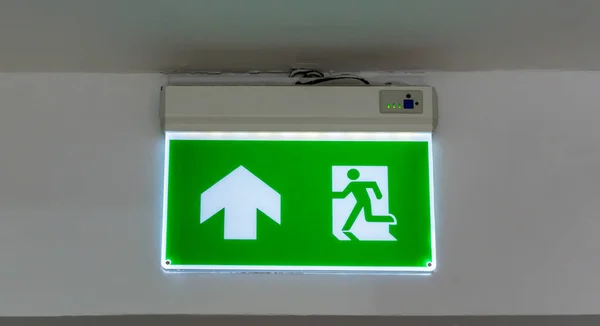 Green emergency exit sign. Direction to the escape way.