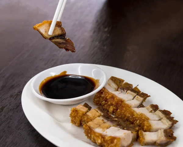 Chopsticks segurando crocante assado barriga de porco servido com preto s — Fotografia de Stock