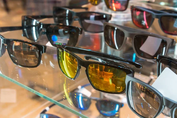 Různé sluneční brýle v obchodě zobrazovat police. — Stock fotografie