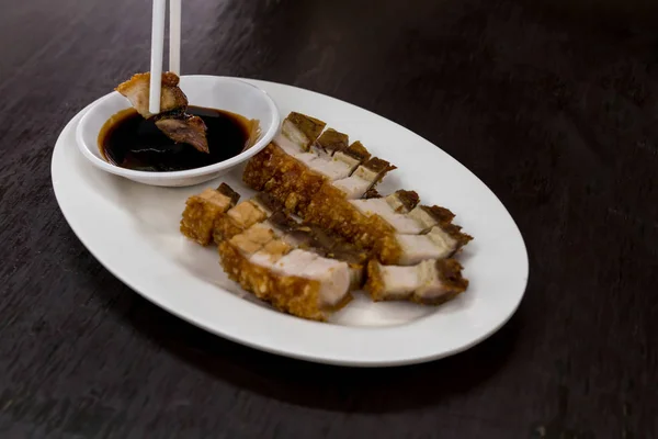 Chopsticks segurando crocante assado barriga de porco servido com preto s — Fotografia de Stock