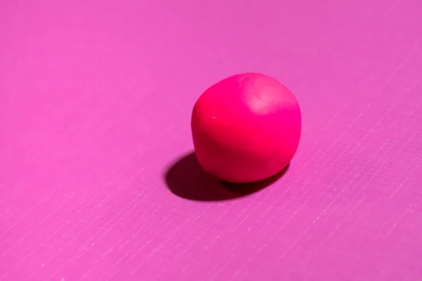 Ενιαίο κόκκινο πλαστελίνη μπάλα σε ροζ φόντο — Φωτογραφία Αρχείου
