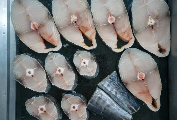 Sommige segmenten van verse rauwe vis op een zwarte achtergrond — Stockfoto