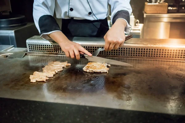 Mão do Chef cozinhar bife de frango na panela quente na frente do costume — Fotografia de Stock