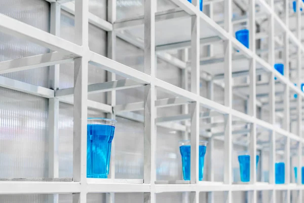 Blaues Wasser in klarem Plastikbecher auf weißem Metallregal structu — Stockfoto