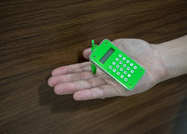 El tutma küçük dijital yeşil hesap makinesi ahşap backg karşı