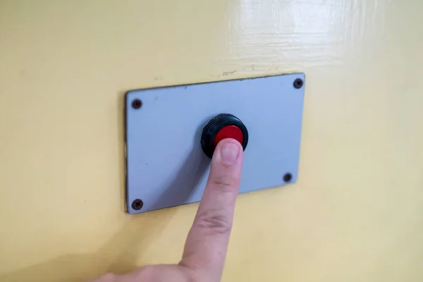 Ett finger når för att trycka på den röda knappen på gul — Stockfoto