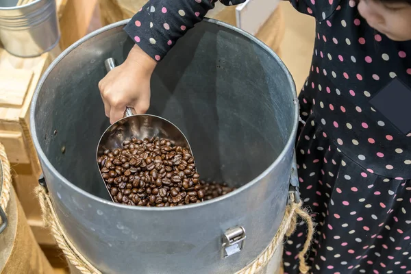 Niño asiático sosteniendo cucharada de acero inoxidable con granos de café tostados en c —  Fotos de Stock