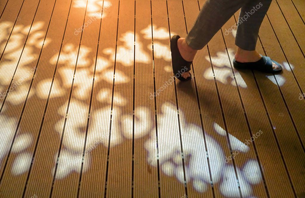 Mujer caminando sobre la pasarela de madera con forma de hojas lightihg